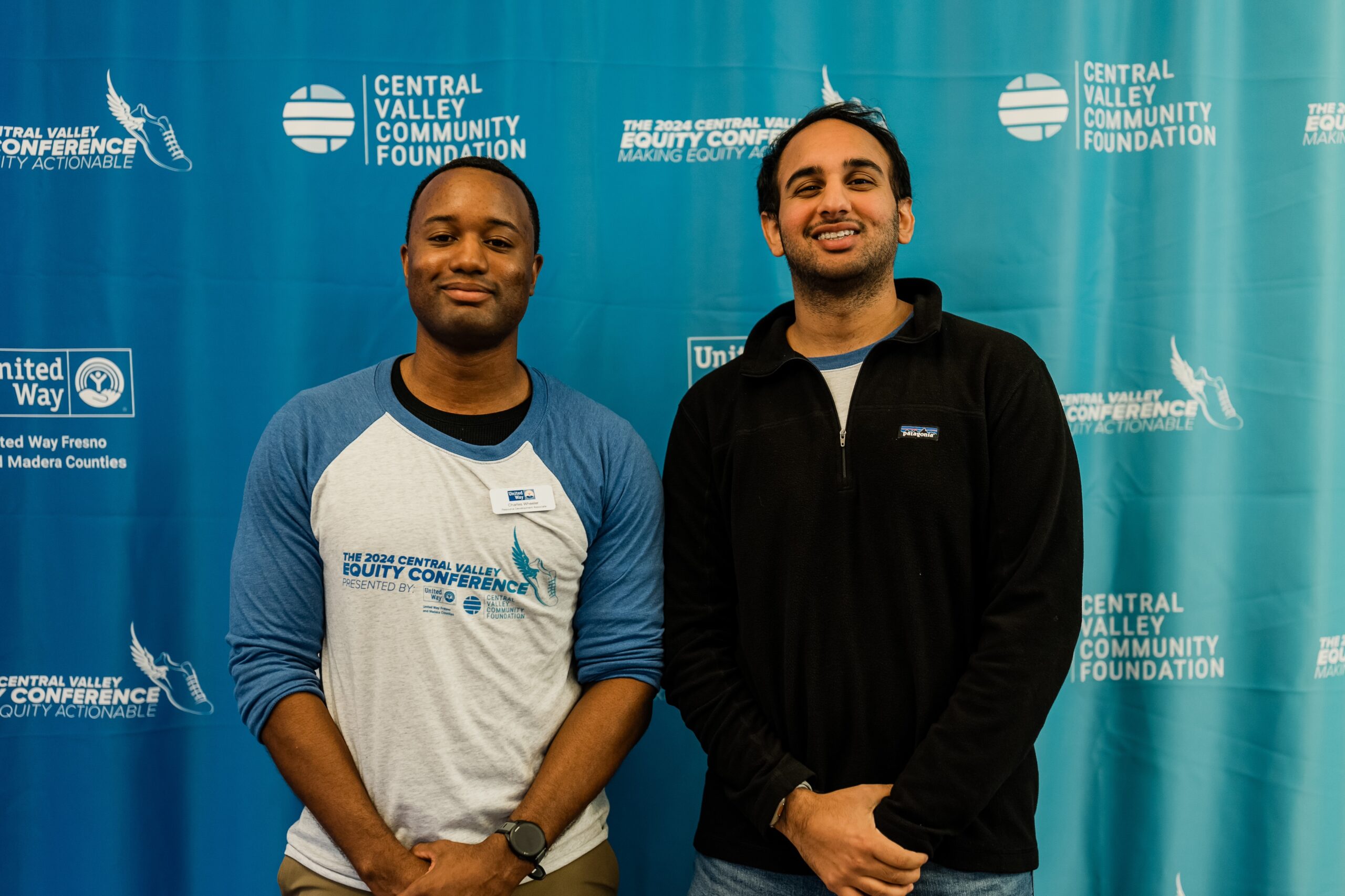 Charles and Sam stand in front of CVEC step and repeat